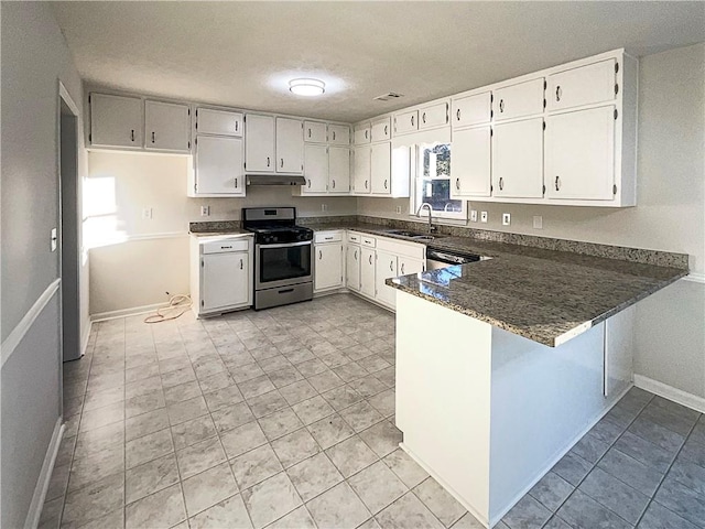 kitchen featuring sink, white cabinetry, stainless steel appliances, kitchen peninsula, and dark stone counters