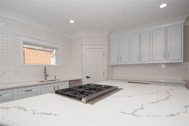 kitchen with tasteful backsplash, light stone counters, sink, and appliances with stainless steel finishes