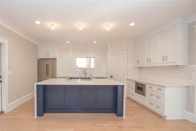 kitchen featuring decorative backsplash, high end fridge, white cabinets, and a kitchen island