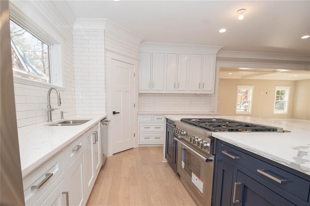 kitchen with blue cabinetry, sink, backsplash, white cabinets, and appliances with stainless steel finishes