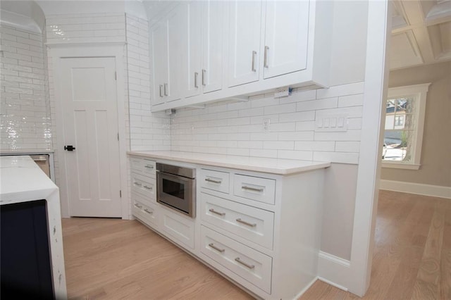 kitchen with tasteful backsplash, light hardwood / wood-style flooring, and white cabinets