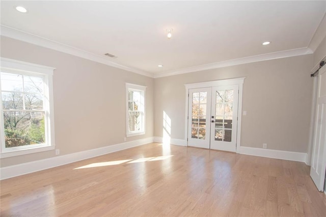 empty room featuring french doors, light hardwood / wood-style flooring, and crown molding