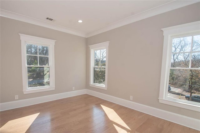 spare room featuring wood-type flooring, a wealth of natural light, and crown molding