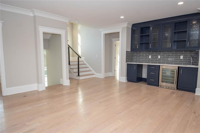 bar with sink, beverage cooler, tasteful backsplash, ornamental molding, and light wood-type flooring