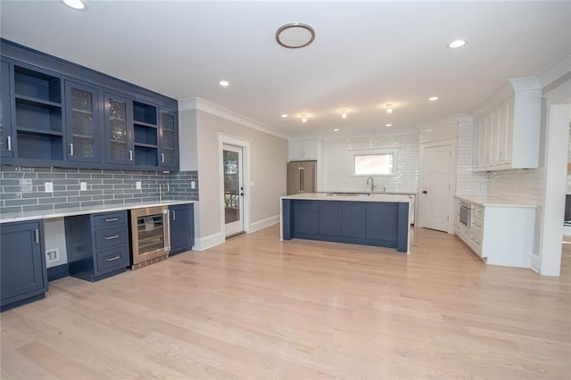 kitchen featuring high end refrigerator, white cabinets, wine cooler, blue cabinetry, and tasteful backsplash