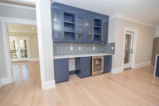 bar featuring french doors, backsplash, blue cabinets, beverage cooler, and light hardwood / wood-style flooring