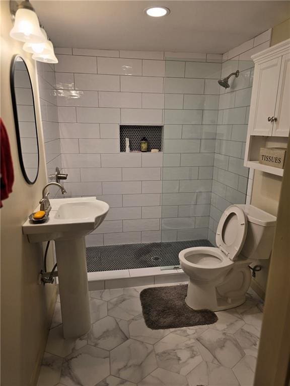 bathroom featuring tiled shower and toilet