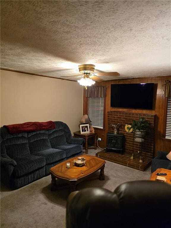 carpeted living room with a wood stove, a textured ceiling, ceiling fan, and wood walls