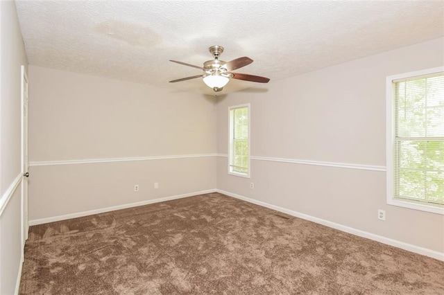 carpeted spare room featuring a textured ceiling, a healthy amount of sunlight, and ceiling fan