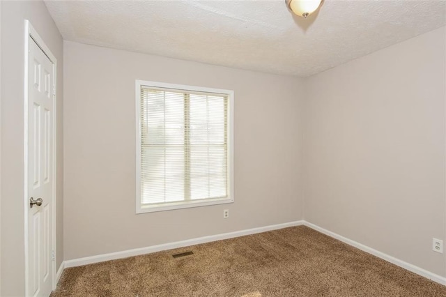 carpeted empty room featuring a textured ceiling