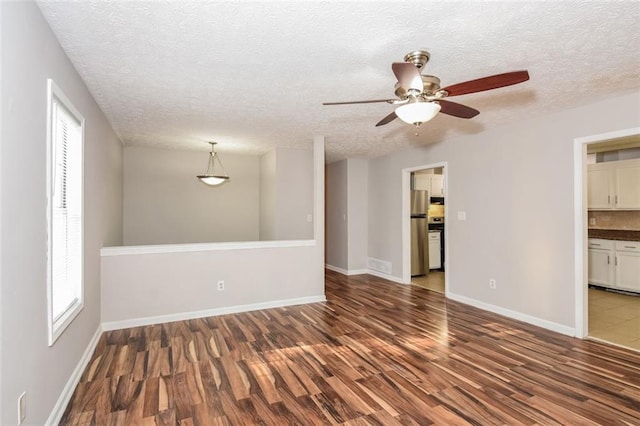 empty room with a textured ceiling, ceiling fan, and dark hardwood / wood-style flooring