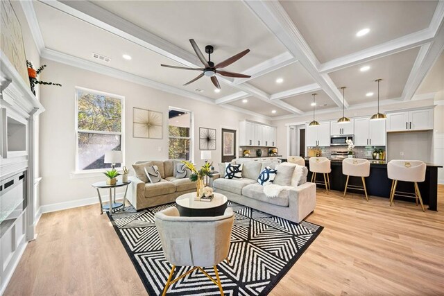 living area featuring visible vents, light wood-style flooring, ornamental molding, ceiling fan, and beamed ceiling