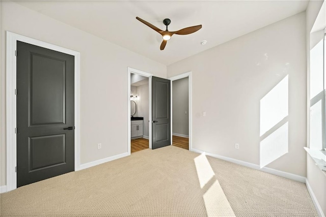 unfurnished bedroom with carpet flooring, baseboards, ensuite bathroom, and ceiling fan