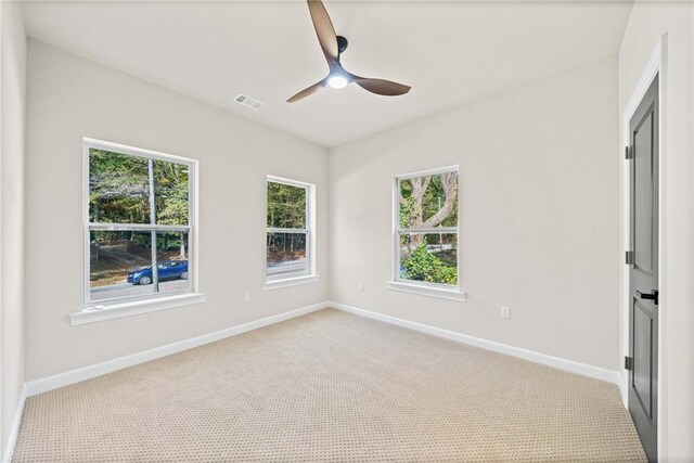 carpeted spare room with a ceiling fan, baseboards, and visible vents
