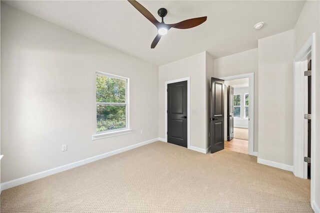 unfurnished bedroom featuring ceiling fan, baseboards, and light carpet