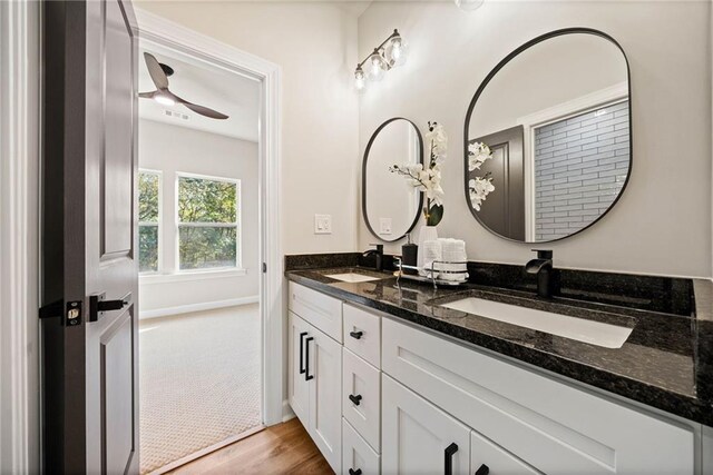 full bath featuring double vanity, wood finished floors, baseboards, and a sink
