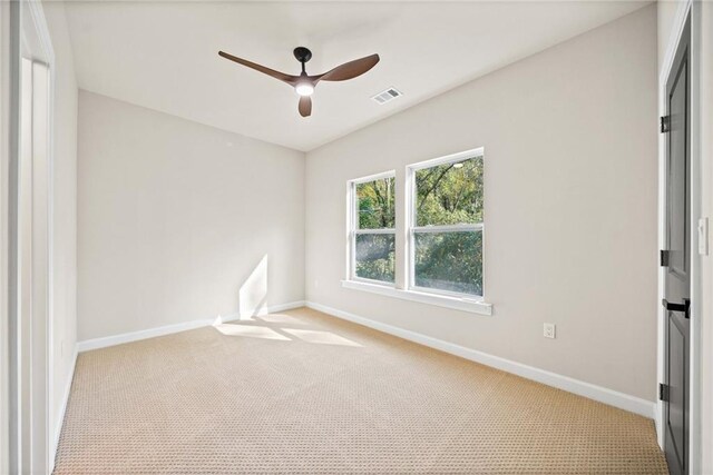 carpeted empty room featuring visible vents, baseboards, and a ceiling fan