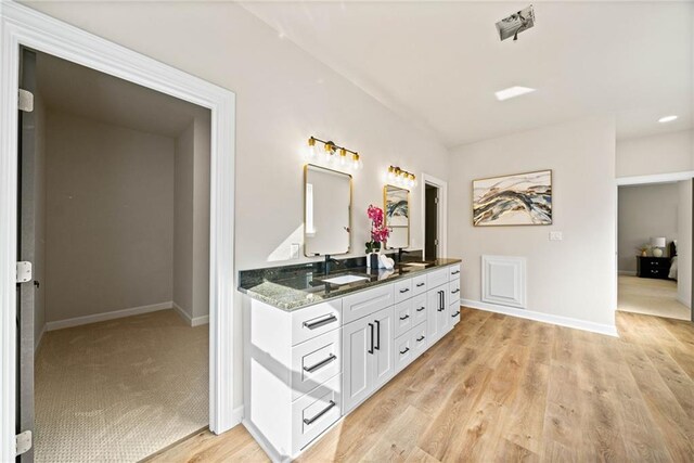 bathroom featuring double vanity, a sink, baseboards, and wood finished floors