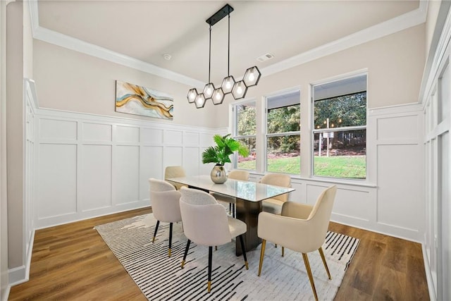 dining area featuring visible vents, crown molding, and a decorative wall
