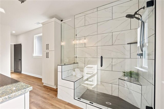 full bath with visible vents, wood finished floors, a stall shower, and baseboards