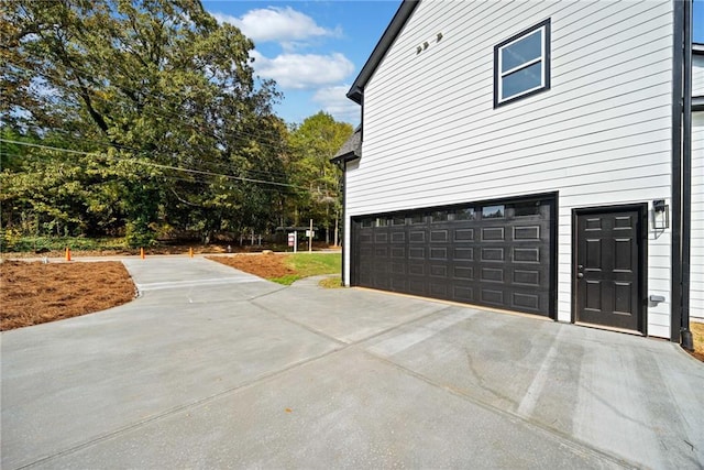 view of home's exterior with concrete driveway and an attached garage