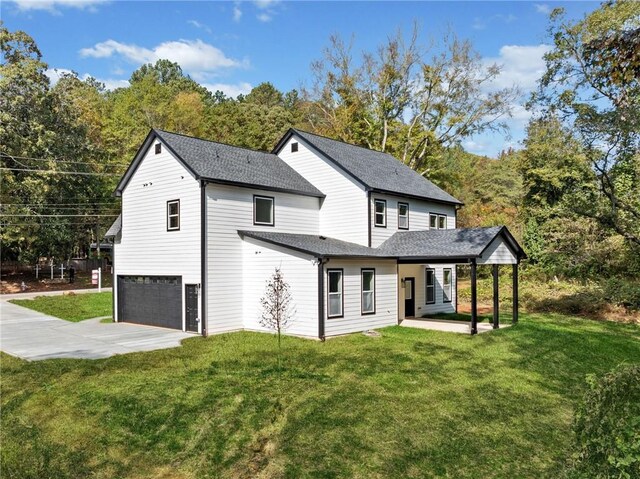 back of property with a garage, a lawn, roof with shingles, and driveway