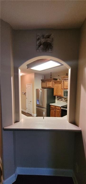 kitchen with decorative backsplash, kitchen peninsula, and appliances with stainless steel finishes