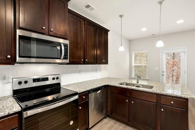 kitchen featuring a sink, stainless steel appliances, a peninsula, decorative backsplash, and visible vents