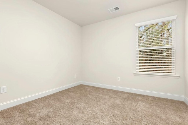 spare room featuring visible vents, baseboards, and light carpet