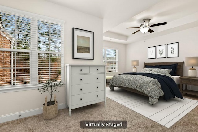 carpeted bedroom with baseboards and a raised ceiling