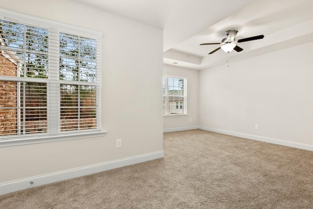 carpeted spare room featuring baseboards, a ceiling fan, and a raised ceiling