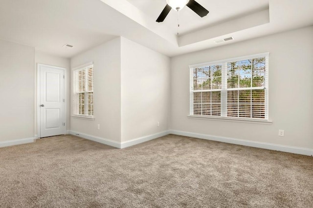 carpeted spare room with visible vents, a ceiling fan, and baseboards