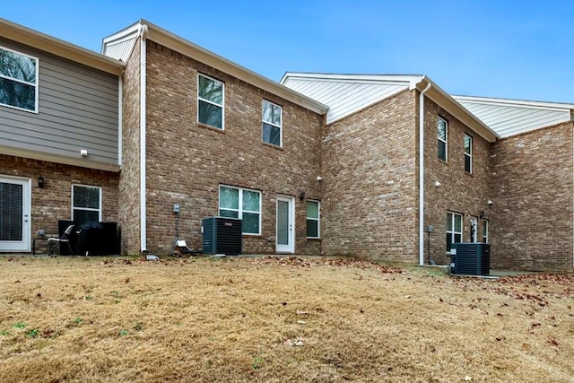 back of house featuring a lawn, brick siding, and central AC unit