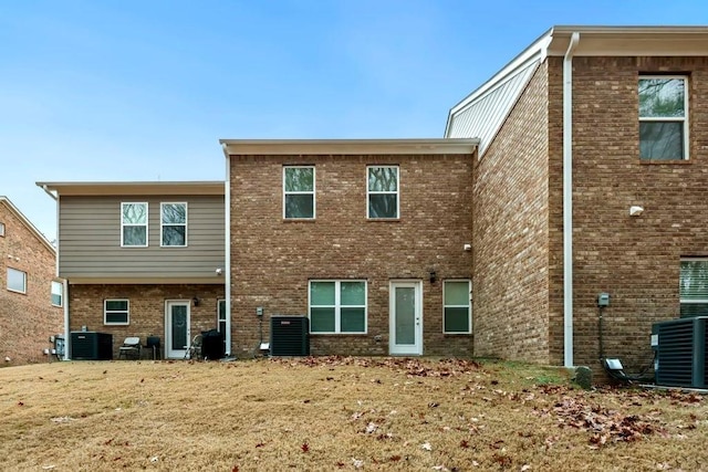 back of property with brick siding and central AC unit