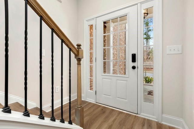 foyer with baseboards, stairs, and wood finished floors