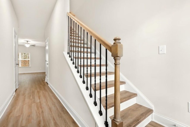 stairs featuring baseboards, ceiling fan, and wood finished floors