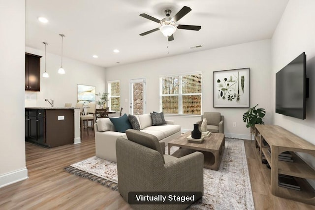 living area featuring baseboards, ceiling fan, light wood-type flooring, and visible vents