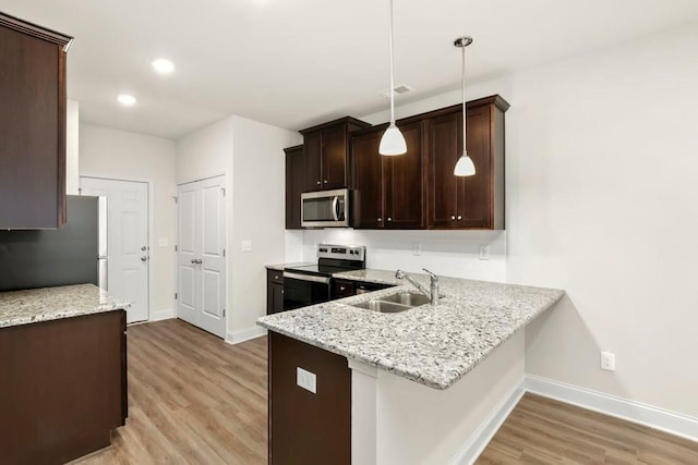 kitchen with a sink, baseboards, light wood-style floors, and stainless steel appliances