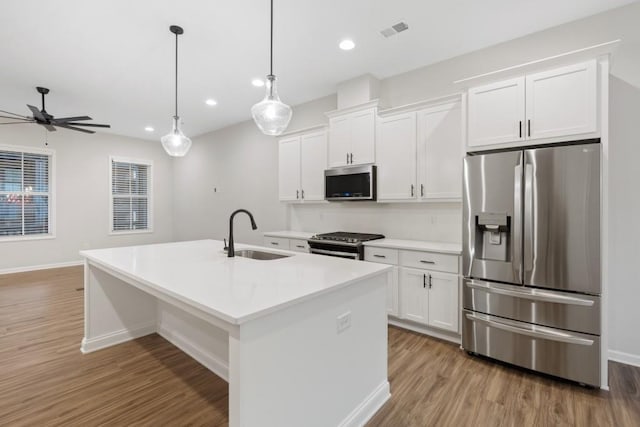 kitchen with a center island with sink, white cabinets, sink, and appliances with stainless steel finishes