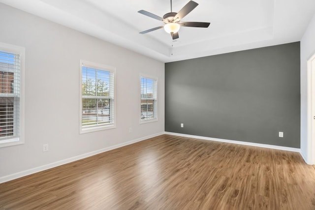 spare room with ceiling fan, wood-type flooring, and a tray ceiling