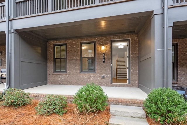 view of exterior entry featuring a porch and a balcony