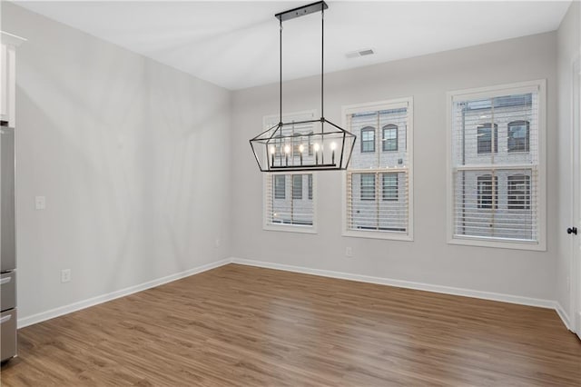 unfurnished dining area featuring wood-type flooring and a chandelier