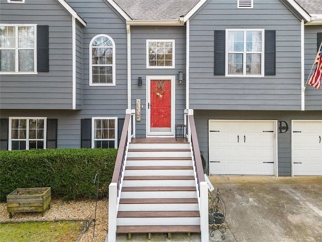 bi-level home featuring an attached garage, concrete driveway, and roof with shingles