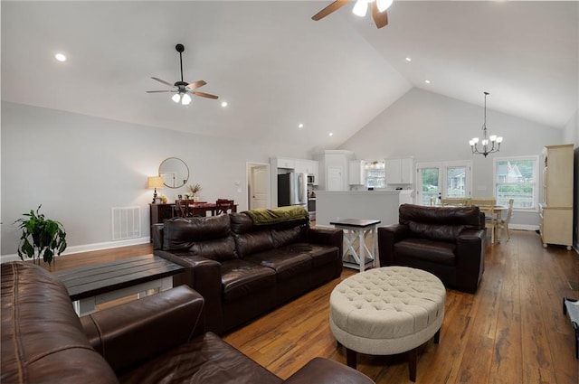 living area with ceiling fan with notable chandelier, high vaulted ceiling, wood-type flooring, and visible vents