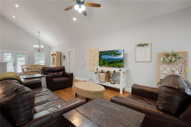 living room featuring light wood-style floors, high vaulted ceiling, baseboards, and ceiling fan with notable chandelier