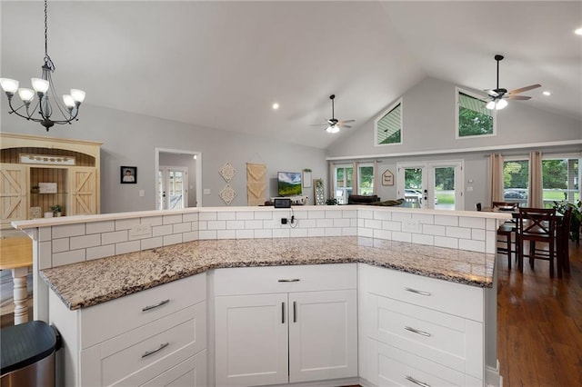 kitchen with tasteful backsplash, open floor plan, white cabinetry, and light stone countertops