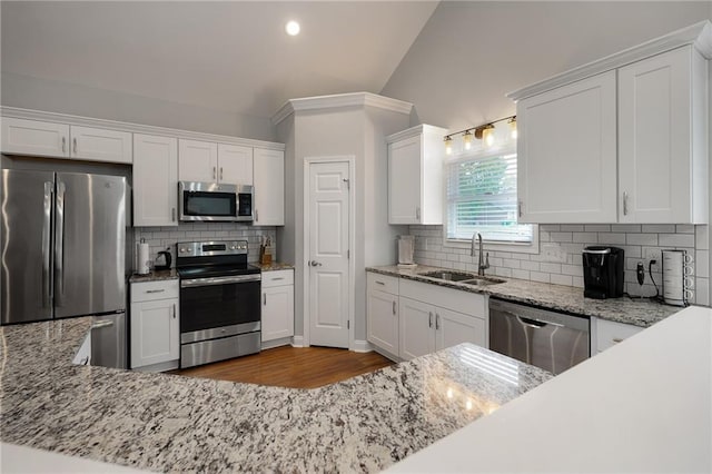 kitchen featuring decorative backsplash, white cabinets, light stone counters, appliances with stainless steel finishes, and a sink