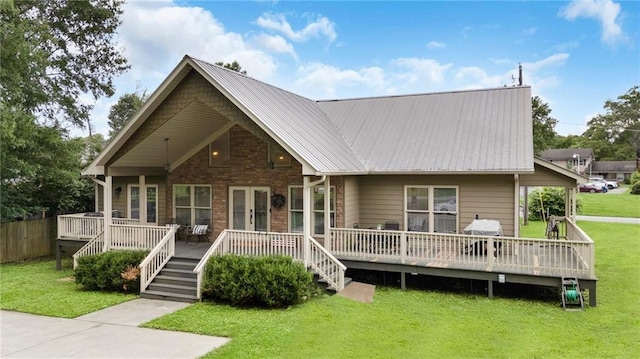 back of property featuring metal roof, a yard, a wooden deck, and french doors