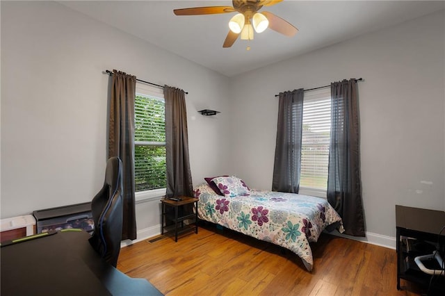 bedroom featuring a ceiling fan, visible vents, baseboards, and wood finished floors