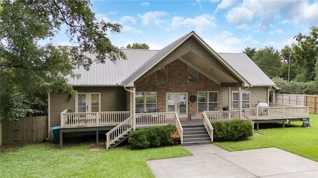 view of front of property with metal roof, fence, a deck, french doors, and a front lawn